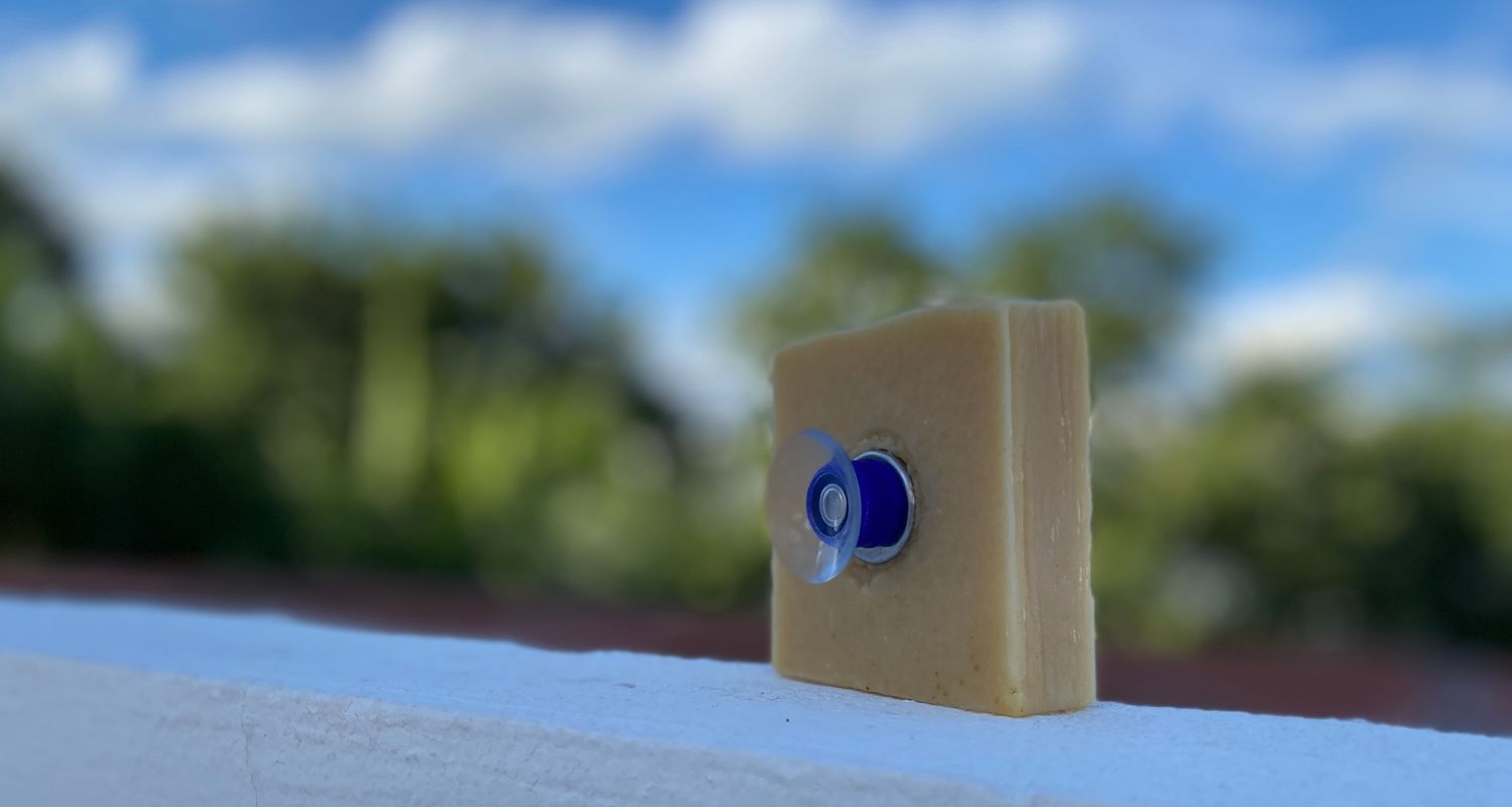 Un savon saponifié à froid avec un porte-savon aimanté pre-installé dans le savon sous le ciel bleu